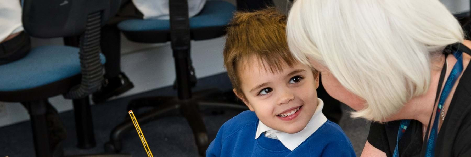 boy in classroom holding a pencil listening to teacher